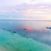 Aerial ocean lifestyle photography showing traditional fishing boats floating on calm water at sunset in Rote, Indonesia