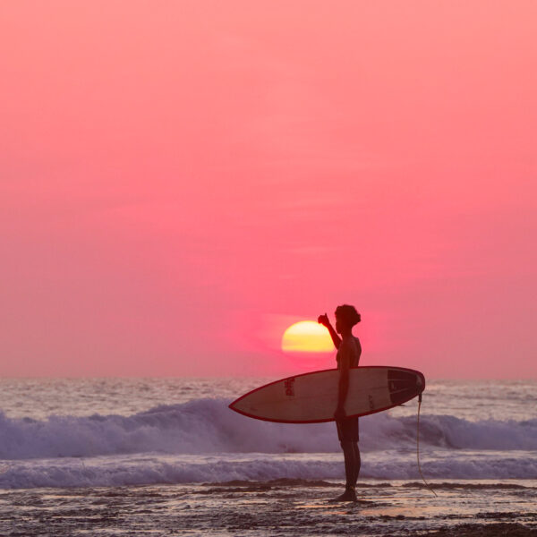 Surf lifestyle photography capturing a young surfer checking ocean conditions at Boa Reef in Rote, Indonesia at sunset