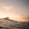 Sunset surf photography showing a surfer carving a wave in warm golden light